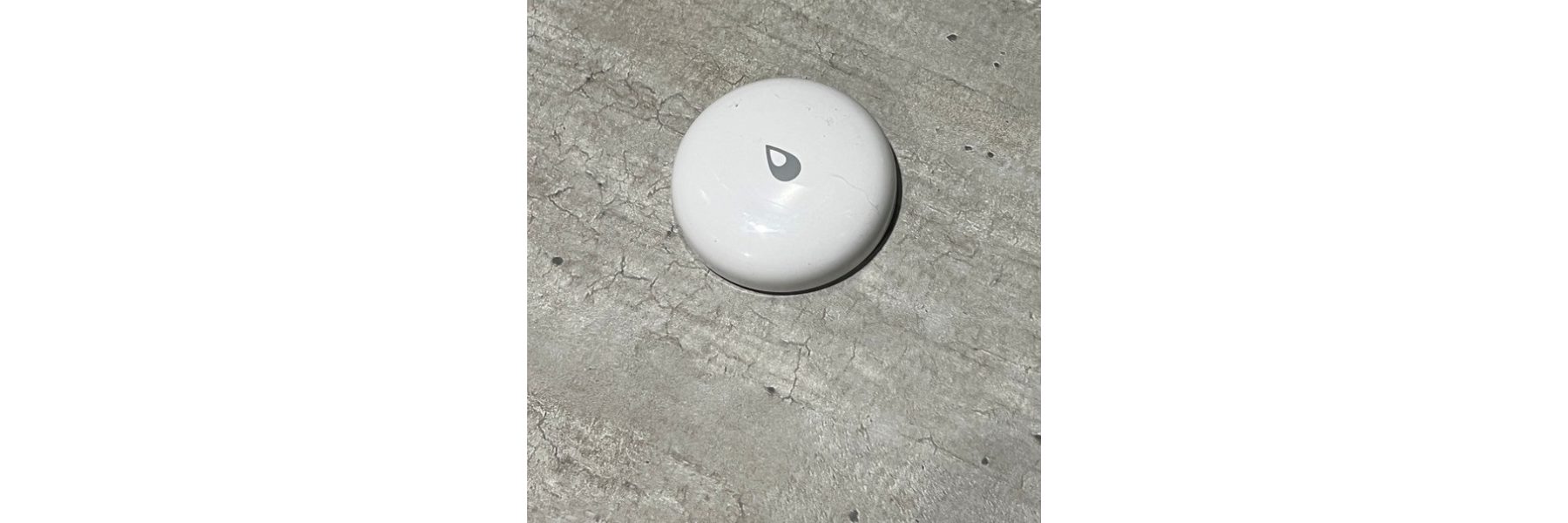 Smart home water leak sensor placed on a laundry room floor to help detect leaks and prevent water damage.